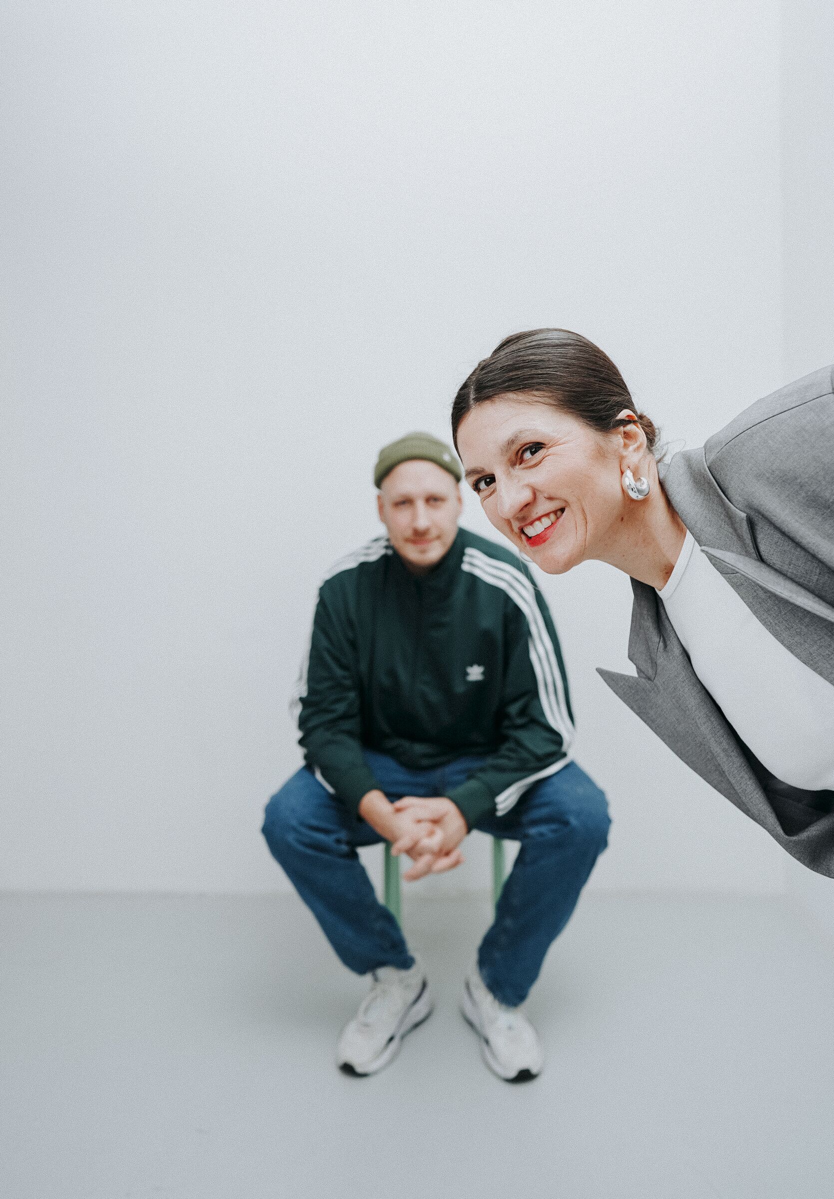 Flo und Alex vom Kollektiv dreimetersiebensiebzig — Flo sitzt im Hintergrund, Alex lehnt sich lachend ins Bild